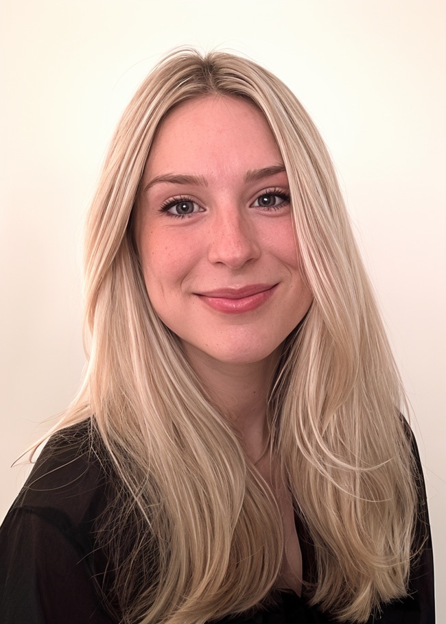 Dr. Julia Poole, with her long blonde hair, smiles warmly at the camera, wearing a black top against a plain background.