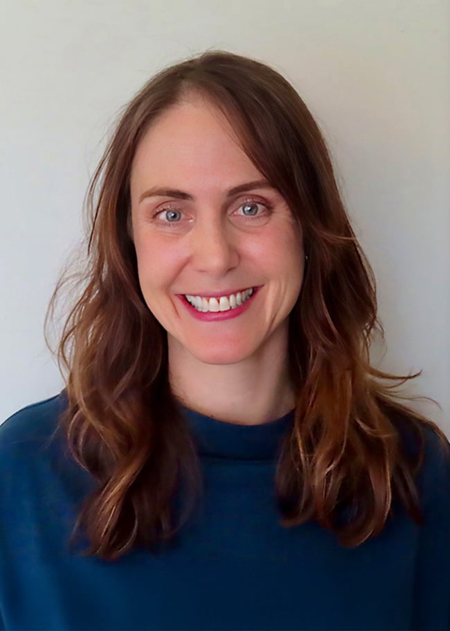 Dr. Rachael Lunt, a woman with long brown hair and a smile, stands against a plain background, wearing a dark blue top.